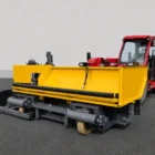 Road widening paver close-up showing the yellow hopper with a red tractor cab behind