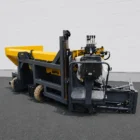 Road widening paver front three-quarter view with operator seat and hydraulic controls