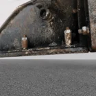 Voegele Super 1800-1 asphalt paver close-up of a greasy metal mounting plate and machine housing